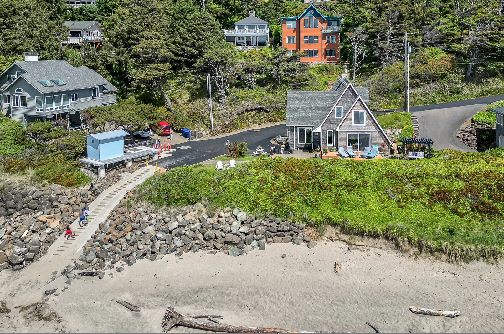 Aerial view of Anchor Court Beach House from the beach showing the house nestled among trees with direct beach access in Lincoln City Oregon